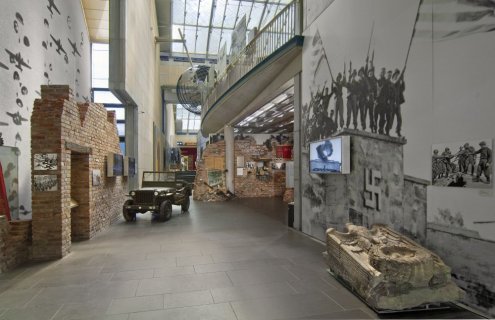 Ein Bereich des Museums zeigt übergroße Fotoaufnahmen, Filmaufnahmen und Relikte aus der NS-Zeit. Ein alter, amerikanischer Jeep steht in der Ausstellung.