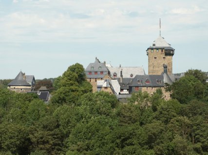 Schloss Burg thront mit seinen mittelalterlichen Türmchen und Erkern über den Baumwipfeln.