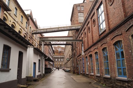 Ein Blick durch die schmale Tuchmacherstraße mit ihren historischen Fabrikgebäuden links und rechts.