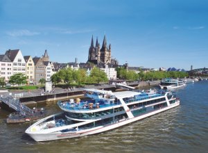 Ein Ausflugsschiff der Köln-Düsseldorfer liegt vor dem Kölner-Altstadtpanorama mit Groß St. Martin und Dom.