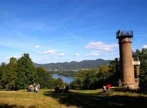 Ein mittelalterlicher Aussichtsturm mit Blick ins Rheintal bei bestem Wetter. Mehrere Besuchergruppen sind unterwegs.
