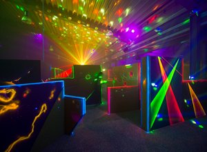 In einem Raum stehen Teile eines großes futuristischen Labyrinths mit fluoreszierenden Projektionen und Lasereffekten.