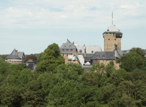 Schloss Burg thront mit seinen mittelalterlichen Türmchen und Erkern über den Baumwipfeln.